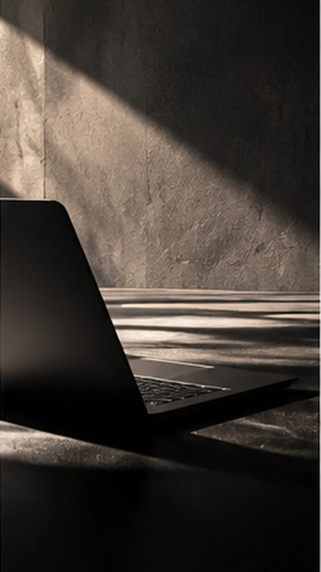 A black laptop on stone with directional light and shadows